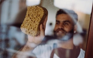 Huishoudhulp Germani maakt de ramen proper in de woonkamer