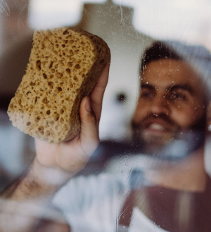 Mannelijke huishoudhulp gaat met spons over ramen